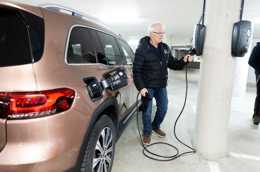 Lennart Bengtsson, boende i föreningen Kaptenen, sticker in laddkontakten i den nya 22-kilowattsladdaren i garaget. Det tar cirka fyra timmar att ladda hans Mercedes EQB från 20 till 80 procent.