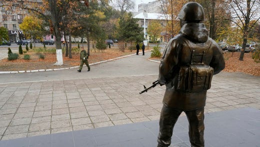 En soldat går förbi en staty vid den ryska styrkans högkvarter i Tiraspol i Transnistrien.