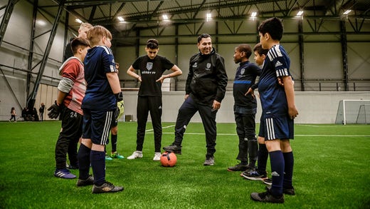 Carlos Morales (mitten) är en av föreningens ungdomstränare. ”Sedan Väsby IK gick i konkurs har en del av Väsby inte haft fotboll. Men med Ken (Ring) har man någonstans gått tillbaka till ursprunget med fotboll för de centrala delarna av Väsby. Vi vill utbilda alla spelare som kommer till klubben”, säger han.