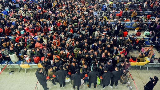 Järnvägsanställda på stationen Hankou i staden Wuhan håller tillbaka passagerare som väntar på att resa hem till sina rötter under ledigheten på kinesiska nyåret.