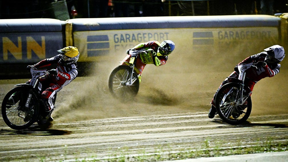 Grzegorz Zengota dei fabbri che indossa l'elmetto giallo davanti al nero Kasper Henrikson (blu) e al compagno di squadra Joel Anderson (bianco).