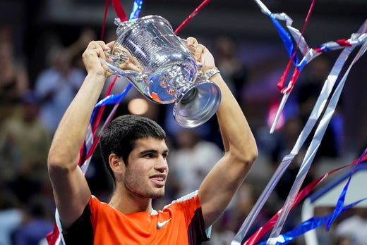 Carlos Alcaraz holds the championship trophy in his hand.