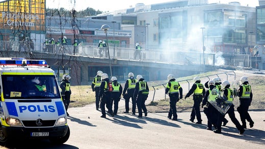Kravallutrustad polis tar sig förbi en barrikad i Norrköping på påskdagen.