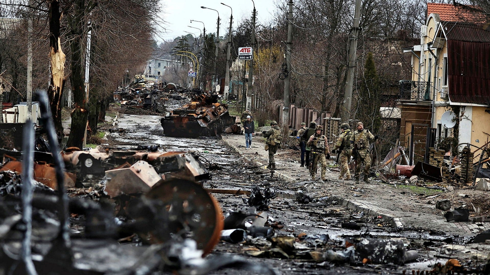 Украинские солдаты проходят мимо сожженной российской военной техники в городе Буча, на северозападе от Киева. Фото:охра Бенсемра/ АФП