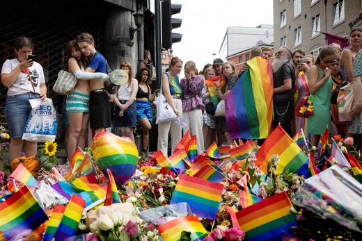 Människor lägger ner blommor och regnbågsflaggor efter skjutningen vid London Pub i Oslo på midsommardagen.