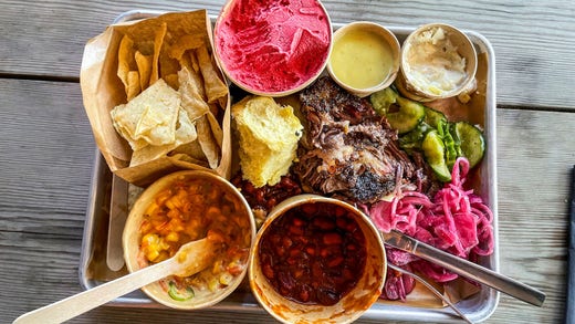 Flera olika tillbehör ingår när man köper BBQ plate brisket. Vill man ha fler får man köpa till. På brickan syns inlagd gurka och rödlök, coleslaw, mjukt bröd, len majssalsa, het bönsalsa och naturella nachos. Dessutom hallonglass.