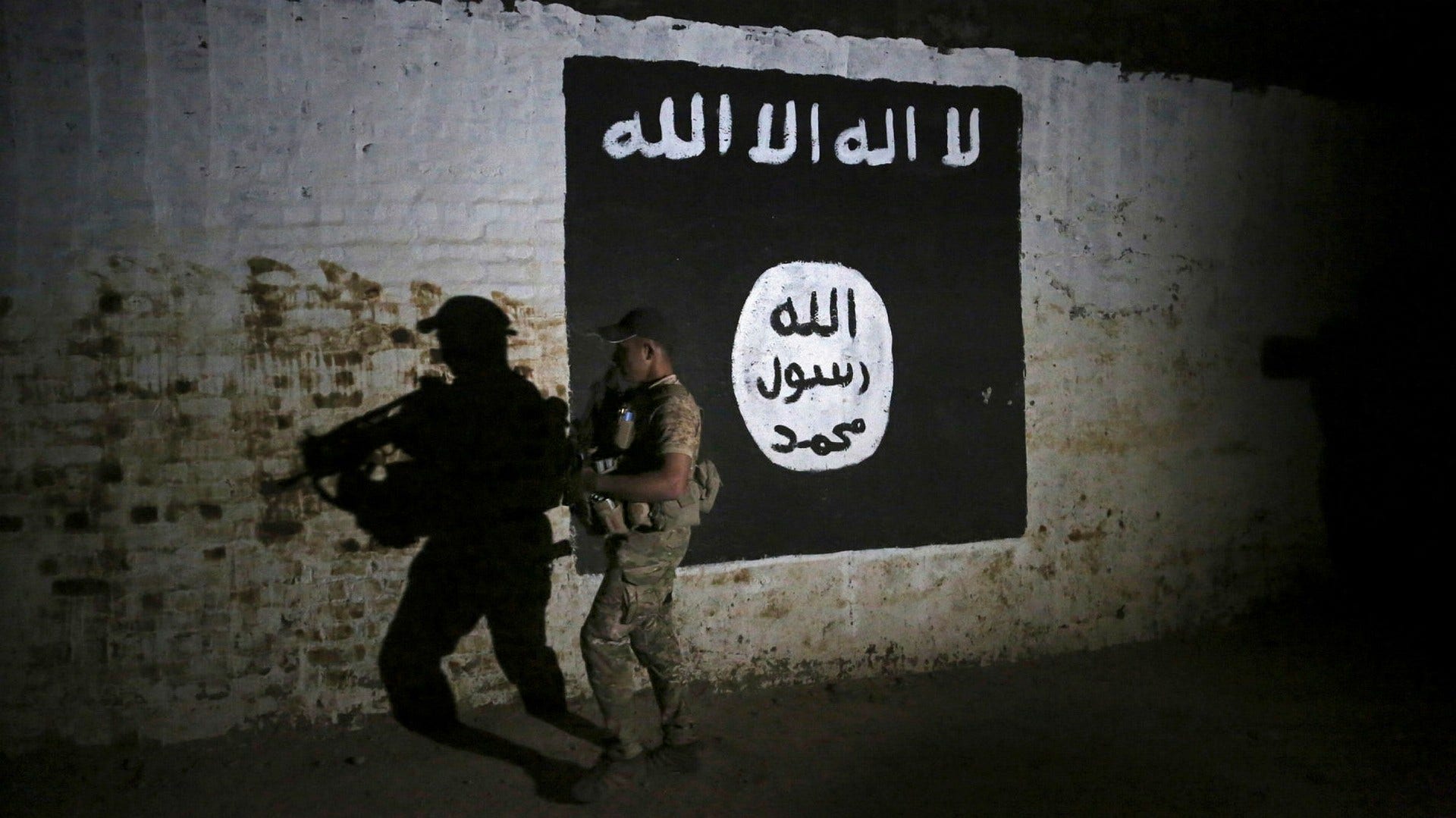 Irakisk soldat inspekterar en tågtunnel smyckad med IS-flagga. Arkivbild från 2017.