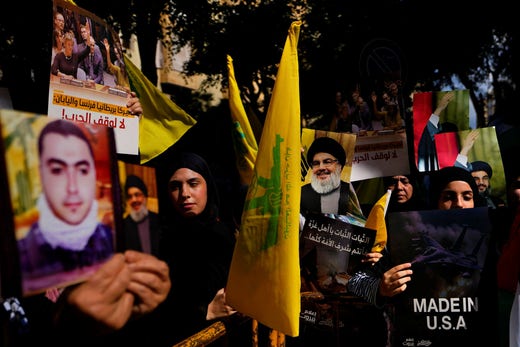 I sostenitori di Hezbollah issano la bandiera della milizia e una foto del suo leader Nasrallah durante una manifestazione a Beirut per i palestinesi di Gaza.