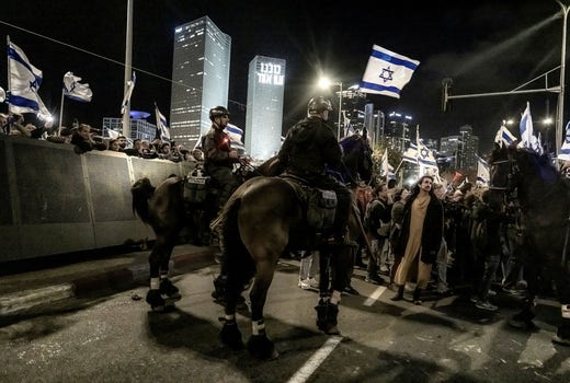 Polisen bildar spärr mellan demonstranter i Tel Aviv och regeringstrogna motdemonstranter – polisen fick arbeta hårt även med polishästar för att hålla cirka 50 motdemonstranter ifrån att drabba samman med tiotusentals anti-regeringsdemonstranter.