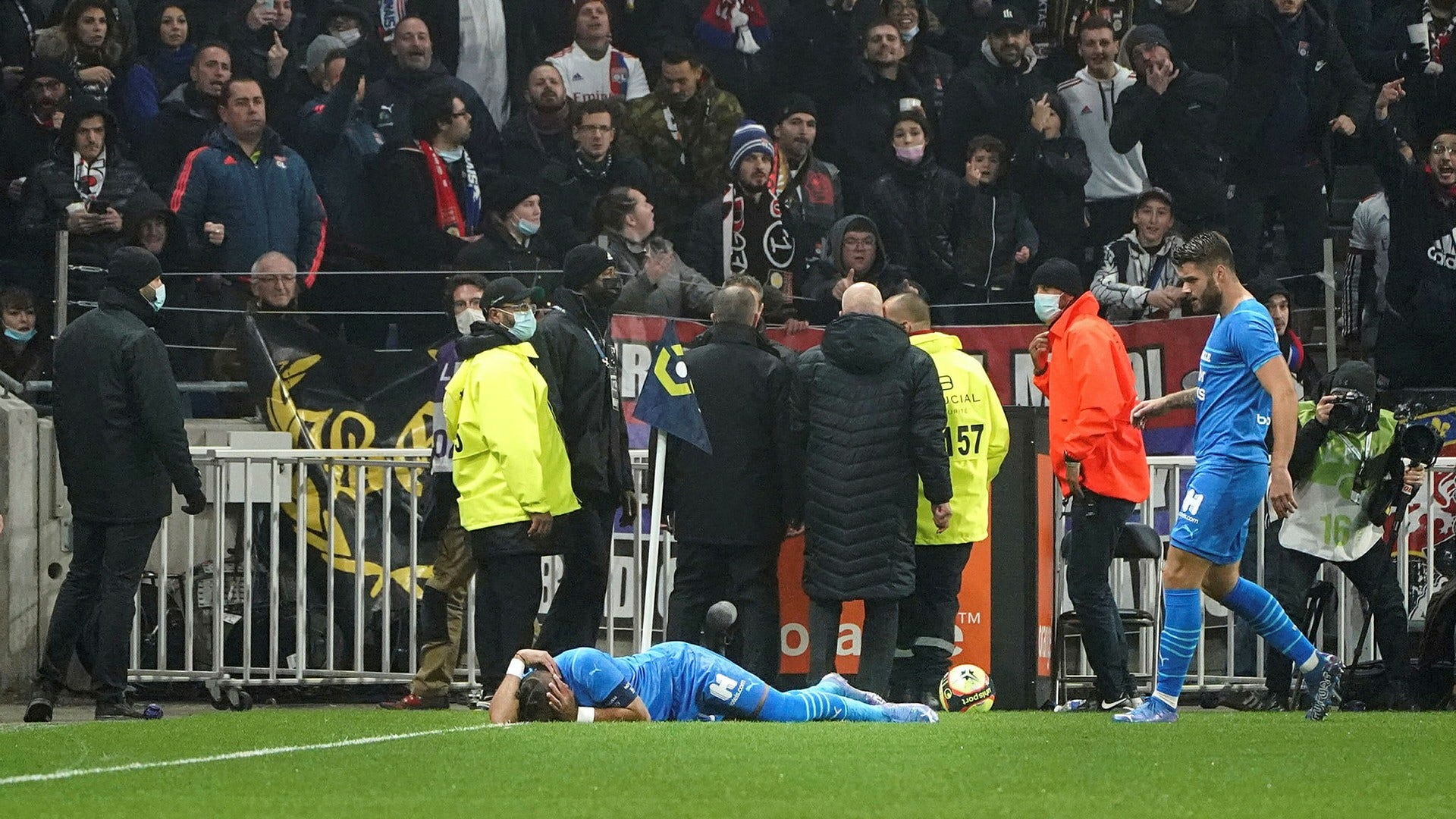 Marseilles Dimitri Payet blir liggande på planen efter att ha fått en flaska kastad i huvudet i bortamatchen mot Lyon. Matchen sköts upp efter skandalen och den franska idrottsministern kallar händelsen för oacceptabel.