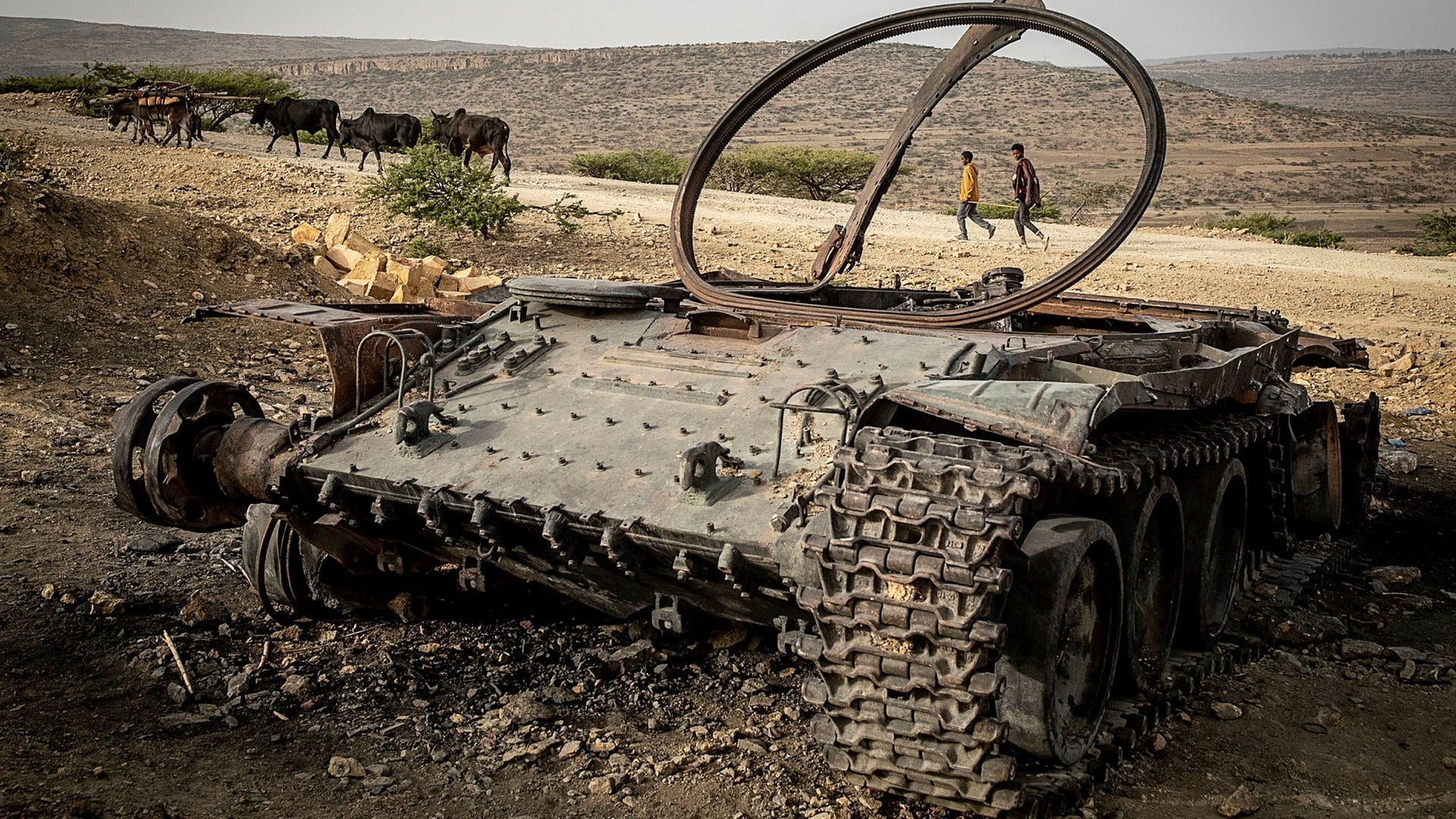Två män i Tigray passerar en tank som sprängts i en drönarattack i konfliktens inledande skede i november i fjol.