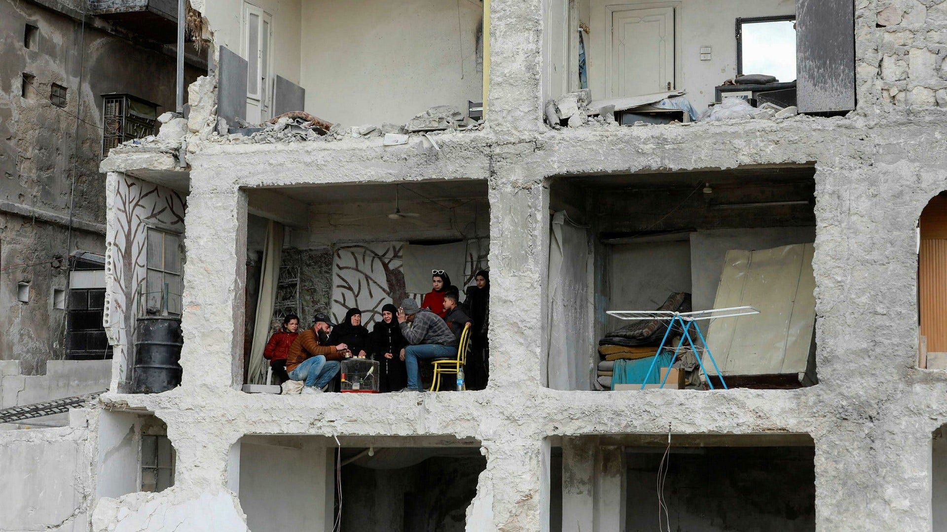 En familj i Aleppo i norra Syrien dricker kaffe i sin lägenhet i ett hus som delvis raserades i jordbävningen den 6 februari.