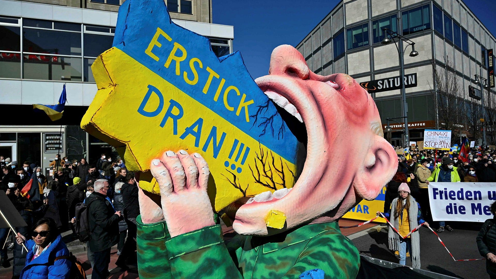 Putin försöker svälja en modell av Ukraina under en demonstration i Berlin mot invasionen.