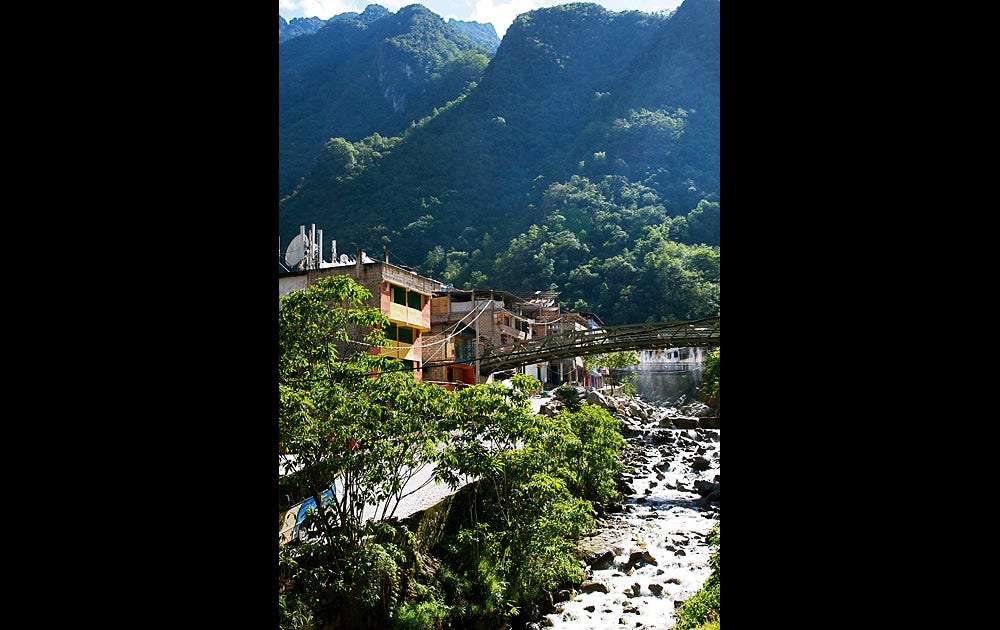 Urubambaflodens stränder är omgivna av höga snöklädda berg. Den smal- spåriga järnvägen passerar genom djungelliknande vegetation innan tåget når slutstationen Aguas Caliente vid foten av Machu Picchu.