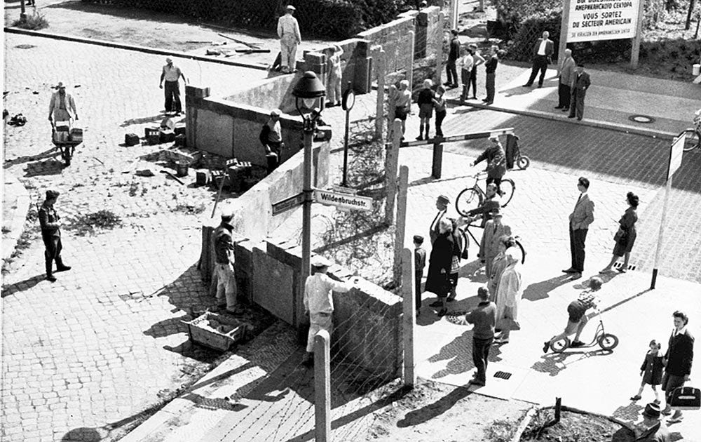 Västberlinare ser på när östtyska soldater bygger upp Berlinmuren 1961.
