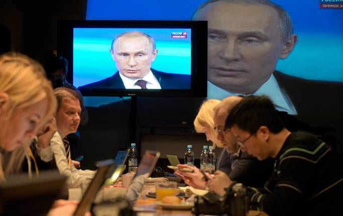 Journalister följer en livesänd tv-tal med Vladimir Putin i april 2014.