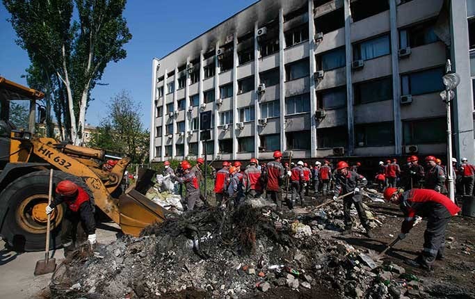 Arbetare i Mariupol bryter igenom barrikaderna till stadshuset i Mariupol med hjälp av en grävskopa.