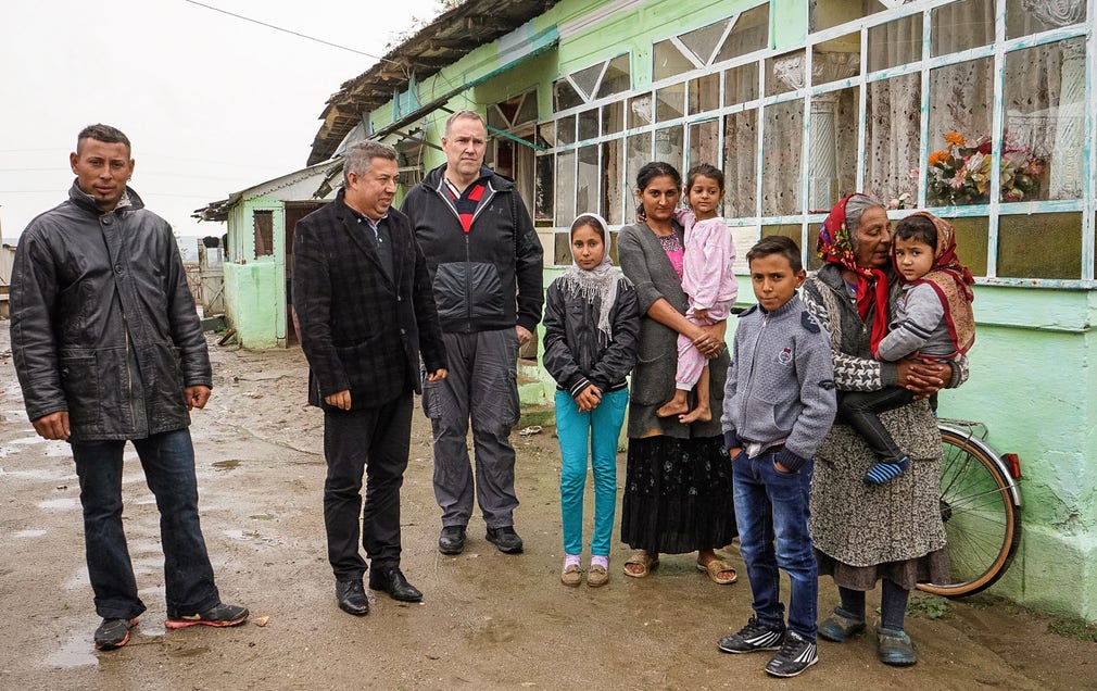 En av de 115 romska familjern i rumänska Gradinari som fått äganderätt till sina bostäder i samarbete mellan kommunen och Hjärta till hjärta. Borgmästaren Iona Mihai är andra person från vänster. Till höger om honom artikelförfattaren.
