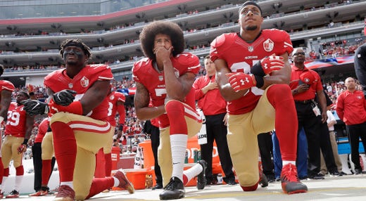 Colin Kaepernick under sin protest flankerad av sympatiserande lagkamraterna Eli Harold och Eric Reid.