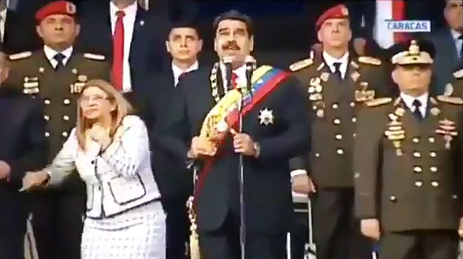President Nicolás Maduro i mitten, hans fru Cilia Flores till vänster och högt uppsatta militärer reagerar på en smäll under presidentens tal.