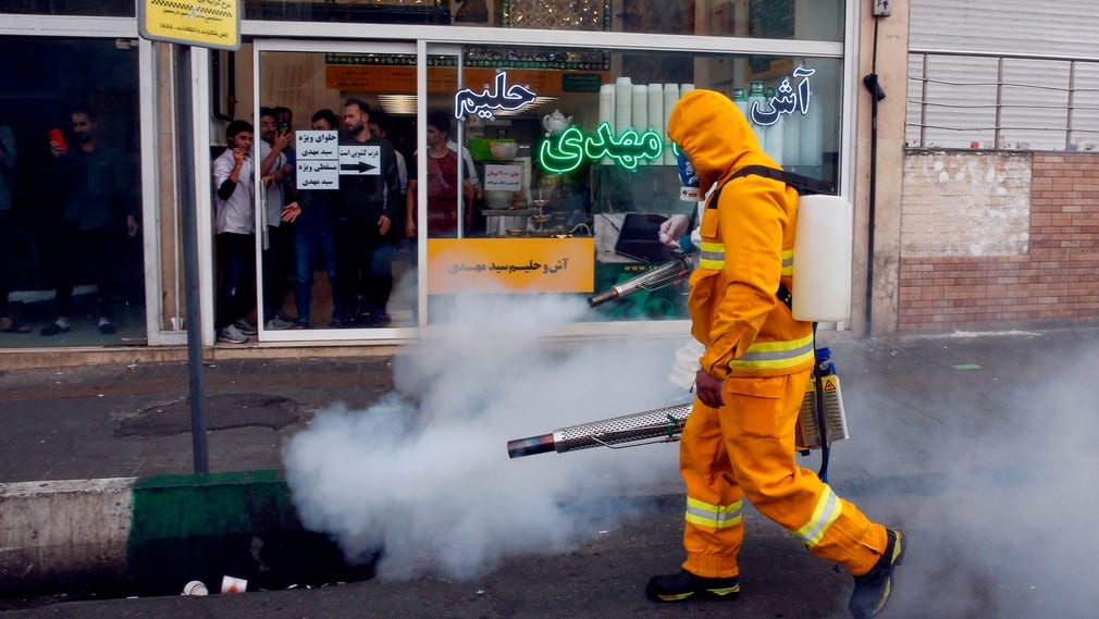 En iransk brandman desinficerar längs en gata i huvudstaden Teheran.