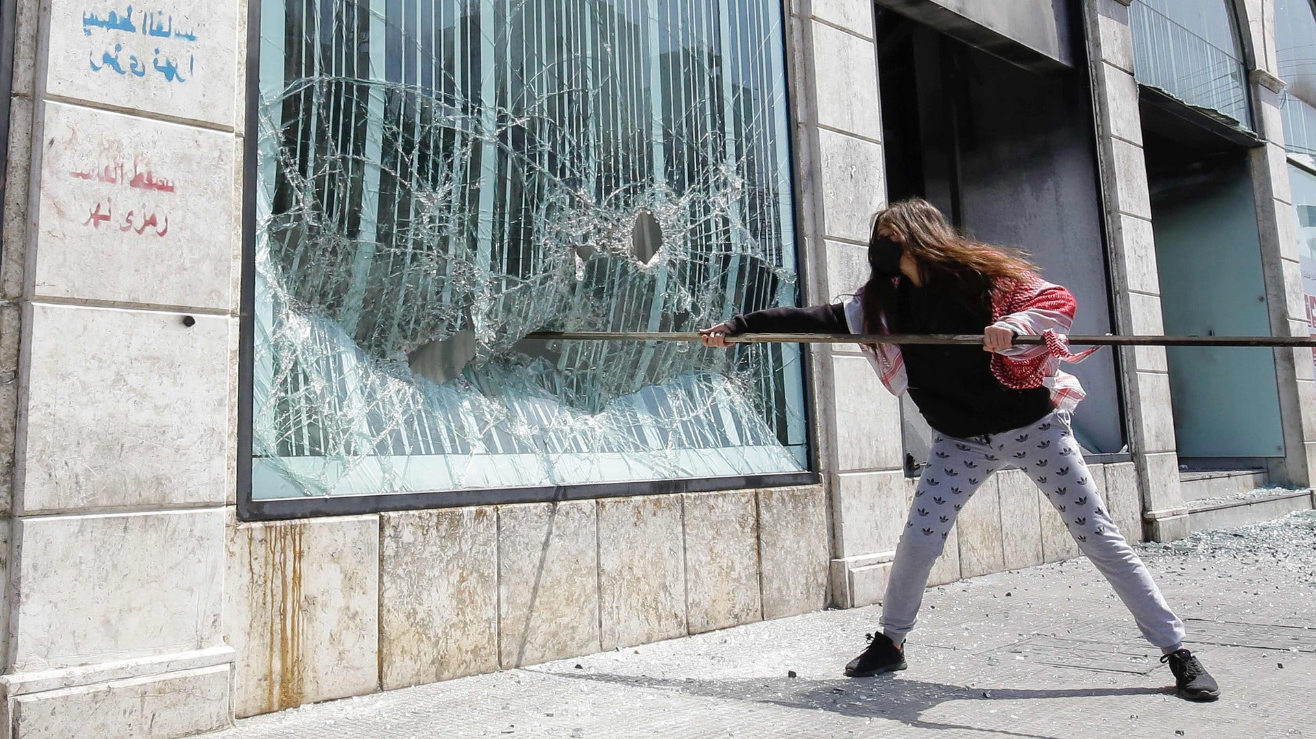 En demonstrant attackerar en bankbyggnad i Tripoli i Libanon.