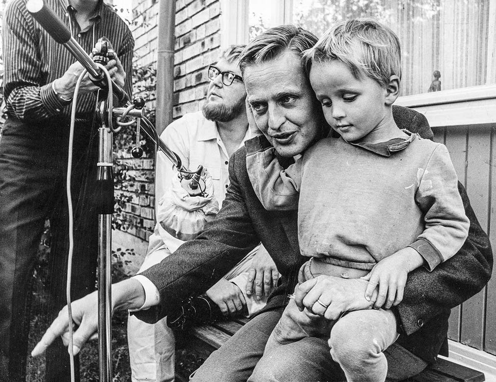 Filmaren Vilgot Sjöman besöker Vällingby 1967 för en intervju om klassamhället med kommunikationsminister Olof Palme till filmen “Jag är nyfiken – gul”. Sonen Mårten tar plats i knäet. Foto: Familjebild.
