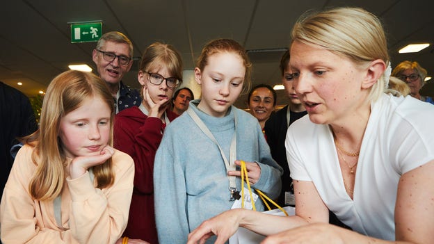 Camilla Lindahl visar upp projekt som arkitektbyrån gjort. Lo och Elvira står närmast och suger åt sig kunskap.