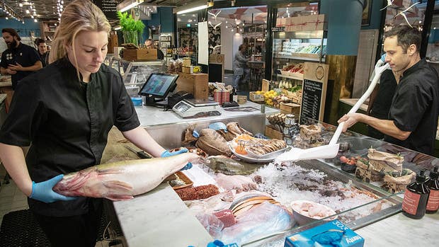 Catharine Stago skär upp och packar fisk.