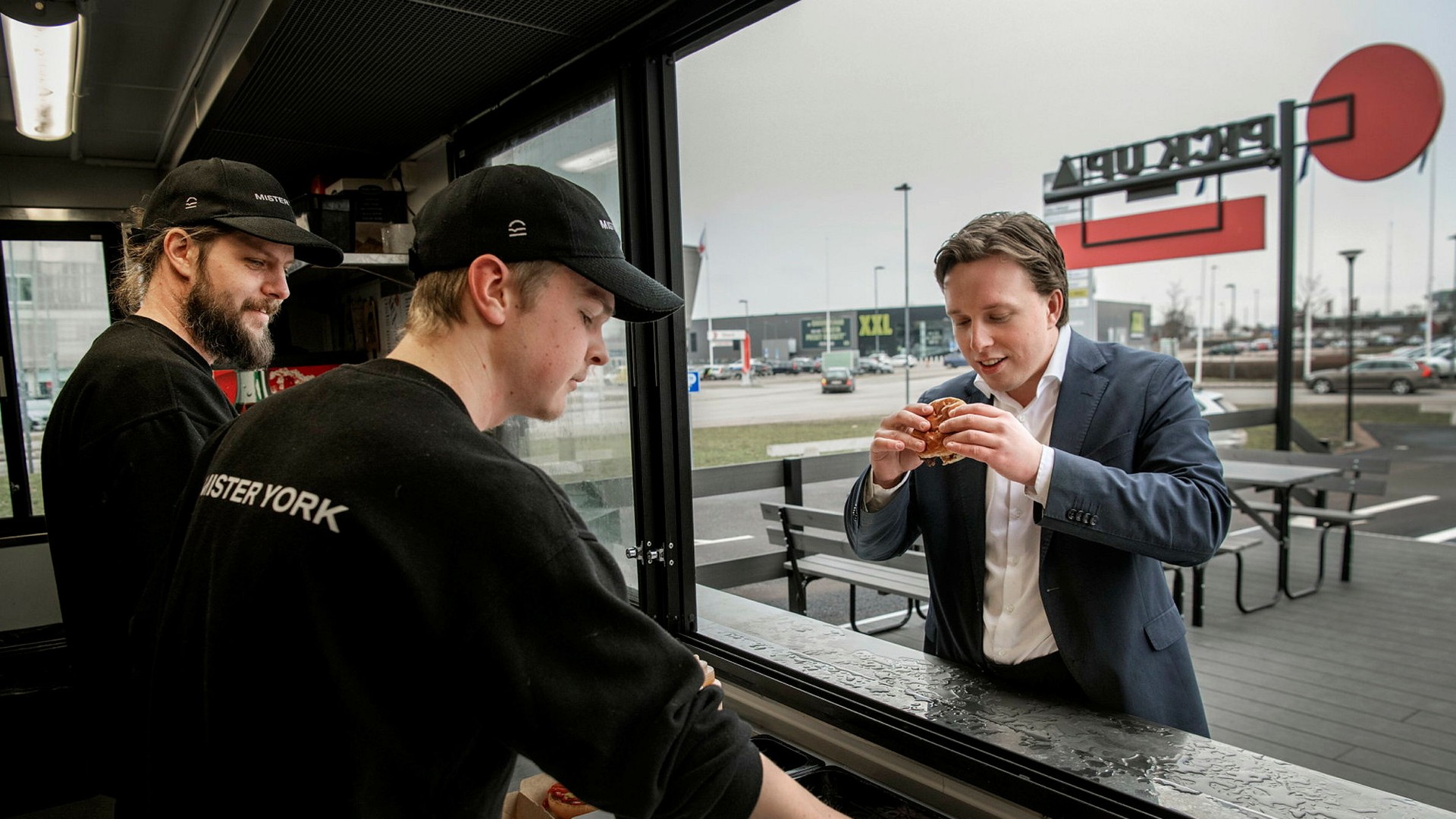 Gustav Haglund får en hamburgare serverad av Alex Ohlsson och Andreas Svallhed.